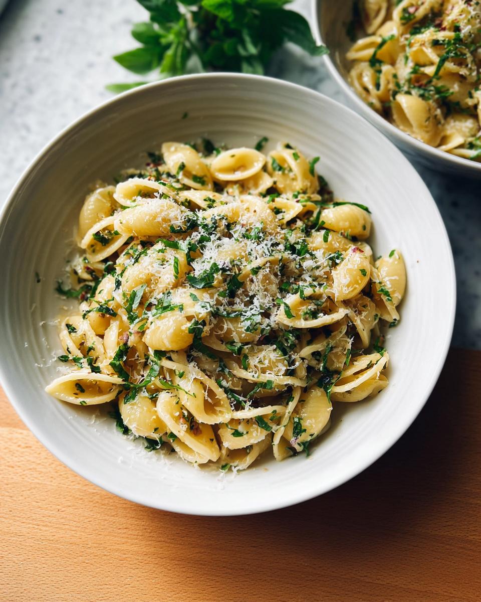 A bowl of Simple Garlic Butter Pasta topped with fresh herbs and grated Parmesan cheese.