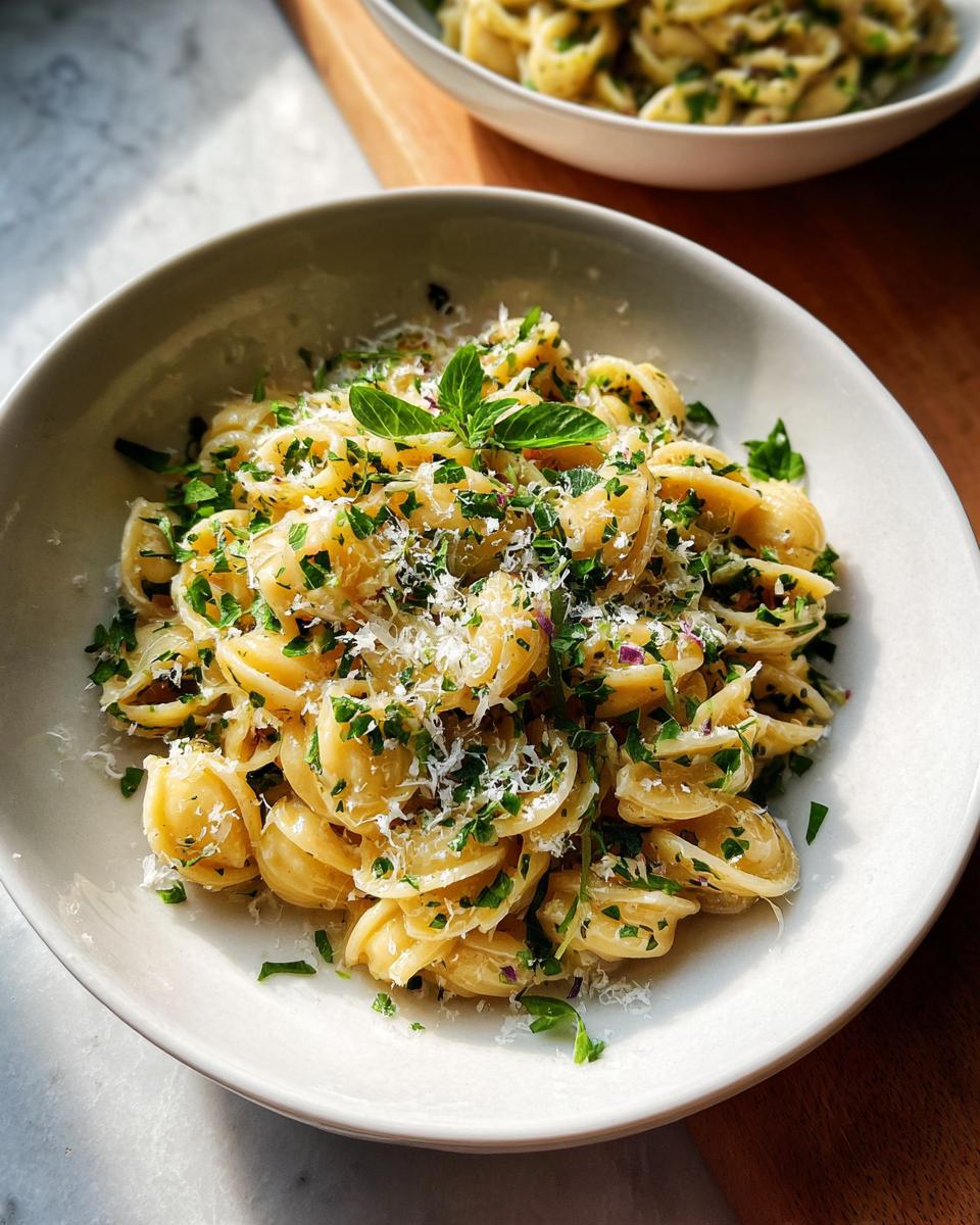 A close-up of Simple Garlic Butter Pasta topped with fresh herbs and grated cheese.