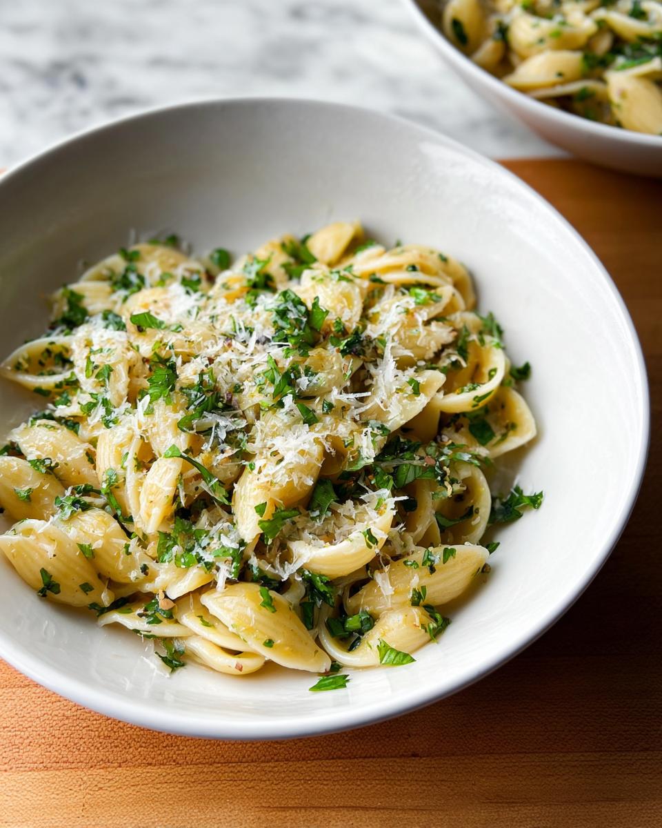 A bowl of Simple Garlic Butter Pasta generously topped with fresh herbs and grated Parmesan cheese.